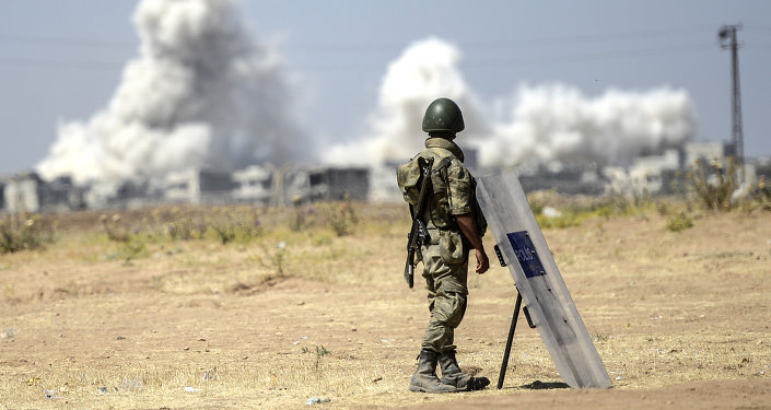 A picture taken from the Turkish side of the border in Suruc, Sanliurfa province, shows a Turkish solider standing as smoke rises from the Syrian town of Kobane, also known as Ain al-Arab, on June 27, 2015