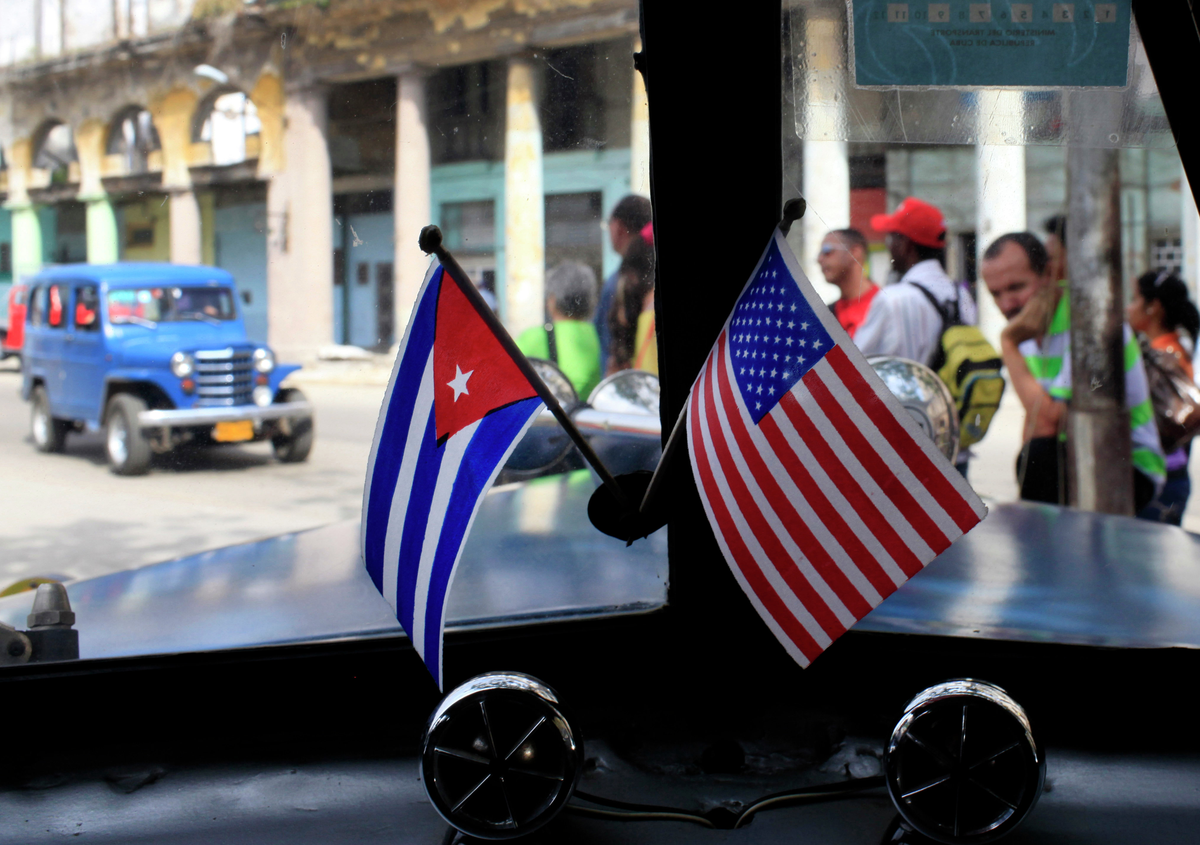 Miniature flags representing Cuba and the United States are displayed on the dash of an American classic car in Havana, Cuba. Miniature flags representing Cuba and the United States are displayed on the dash of an American classic car in Havana, Cuba.