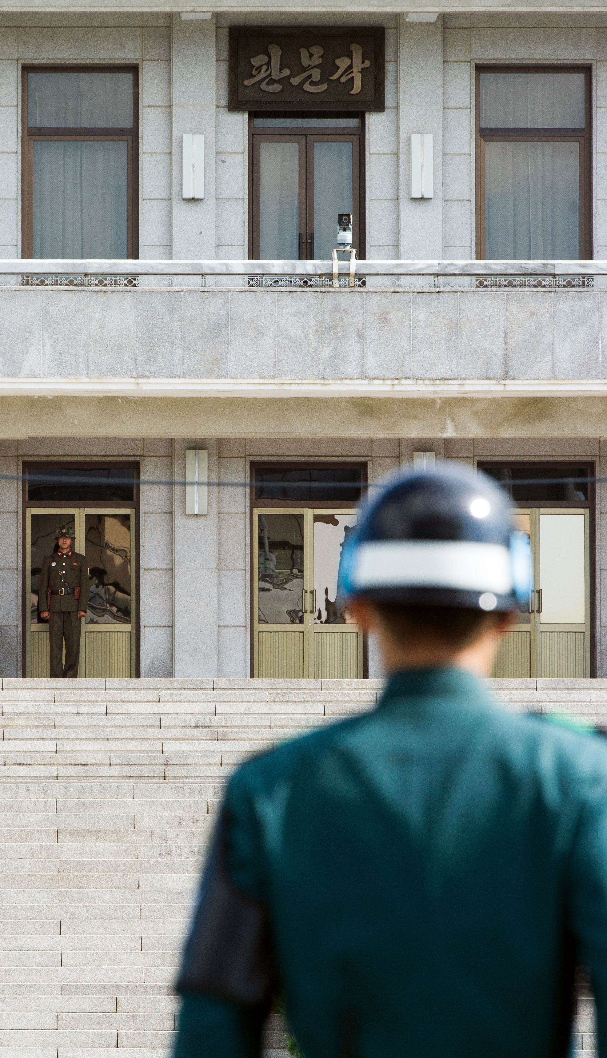 A South Korean JSA guard (front R) and North Korean guard (L) stand guard opposite each other at the border of the truce village of Panmunjom in the Demilitarized zone (DMZ) dividing the two Koreas. File photo.